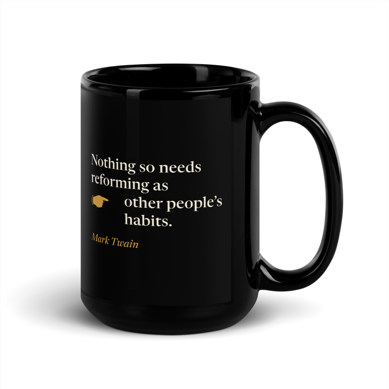 Black mug, handle on the right: "Nothing so needs reforming as other people's habits." Mark Twain, with a pointing hand.
