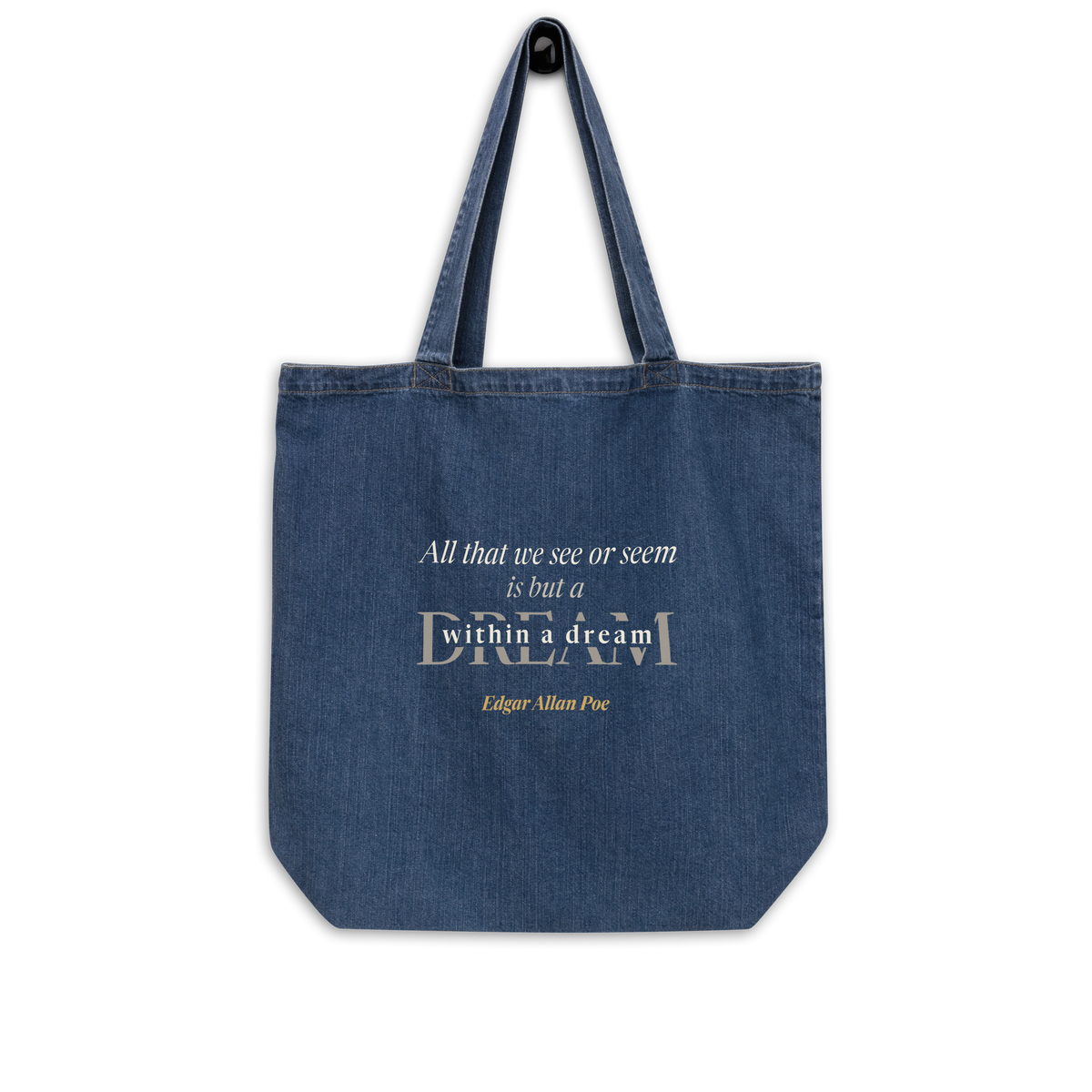 Indigo denim tote bag hanging, front: Poe's "A Dream Within a Dream" in cream and warm matte gold.