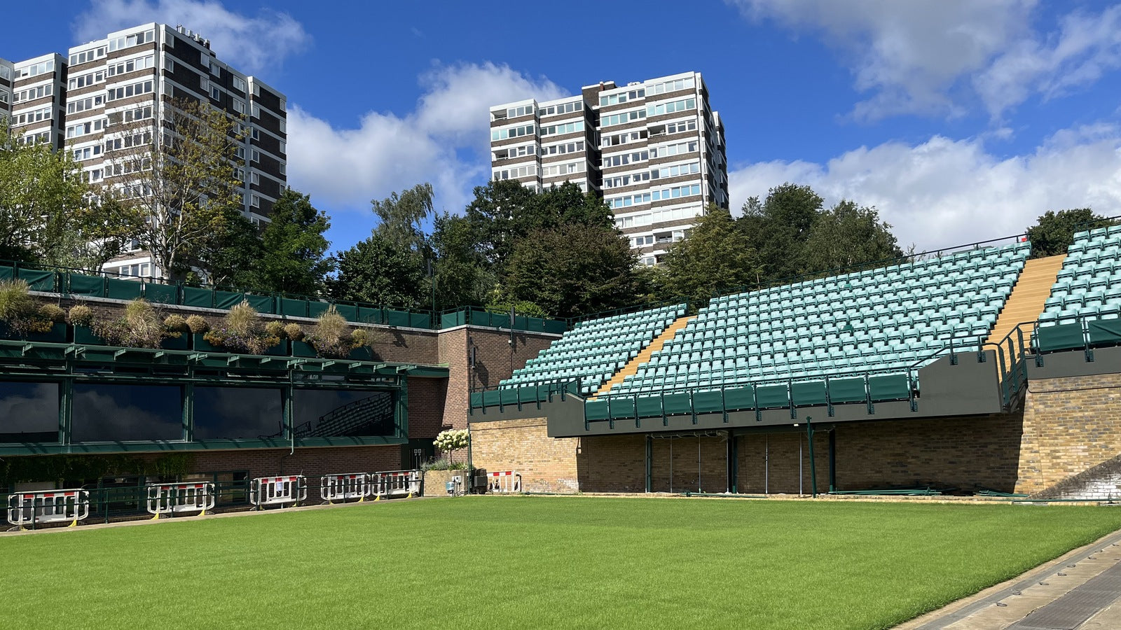 Wimbledon Court 18, All England Club — lush grass court, empty stands. CC BY-SA 4.0.