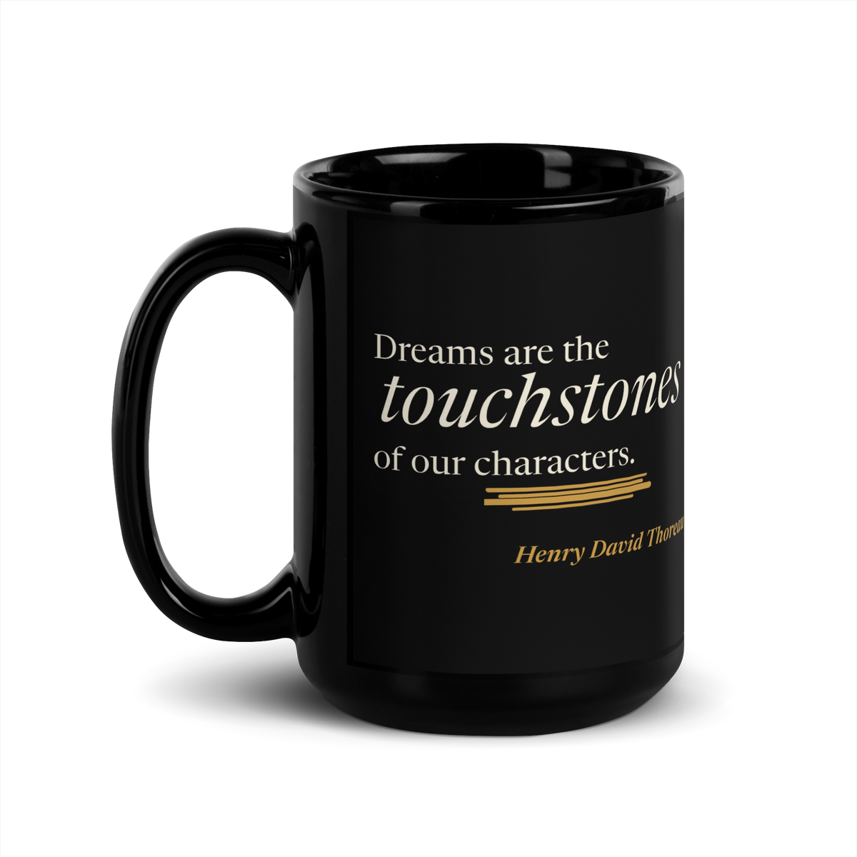 Black 15 oz mug, handle on left: Thoreau's "Dreams are the touchstones of our characters." above a warm matte gold streak.