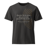 Black organic t-shirt, front: “I live my life in circles that grow wide…” Rilke, inside broken warm arcs.