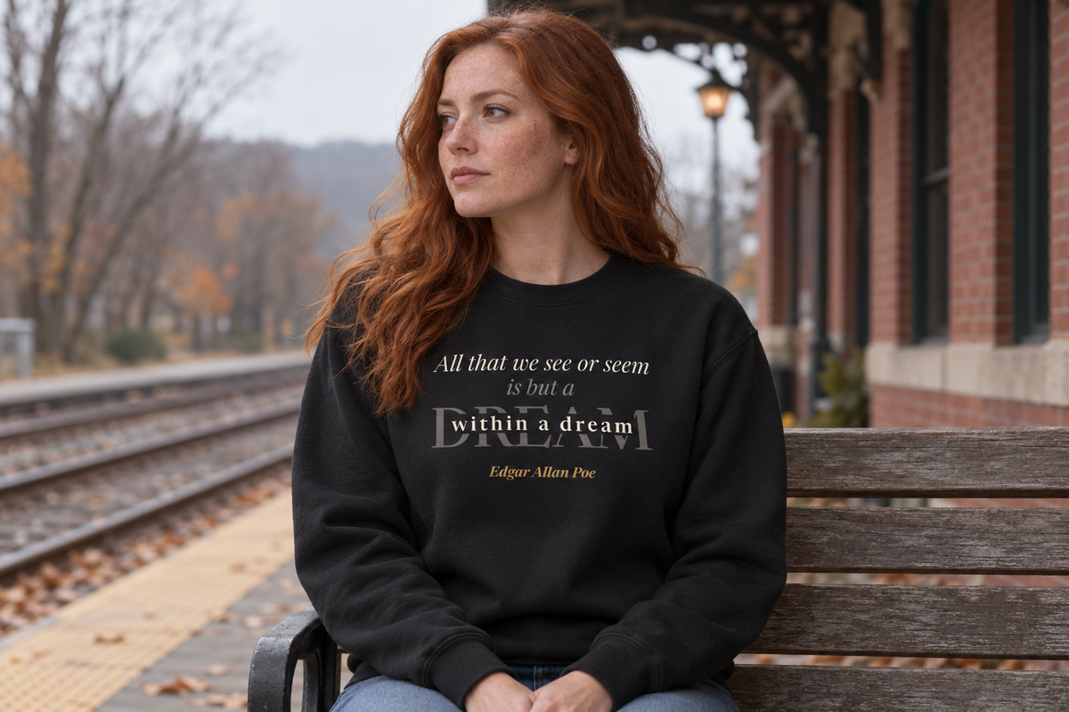 Red-haired woman on a train platform in fall wearing the A Dream Within a Dream — Edgar Allan Poe sweatshirt.
